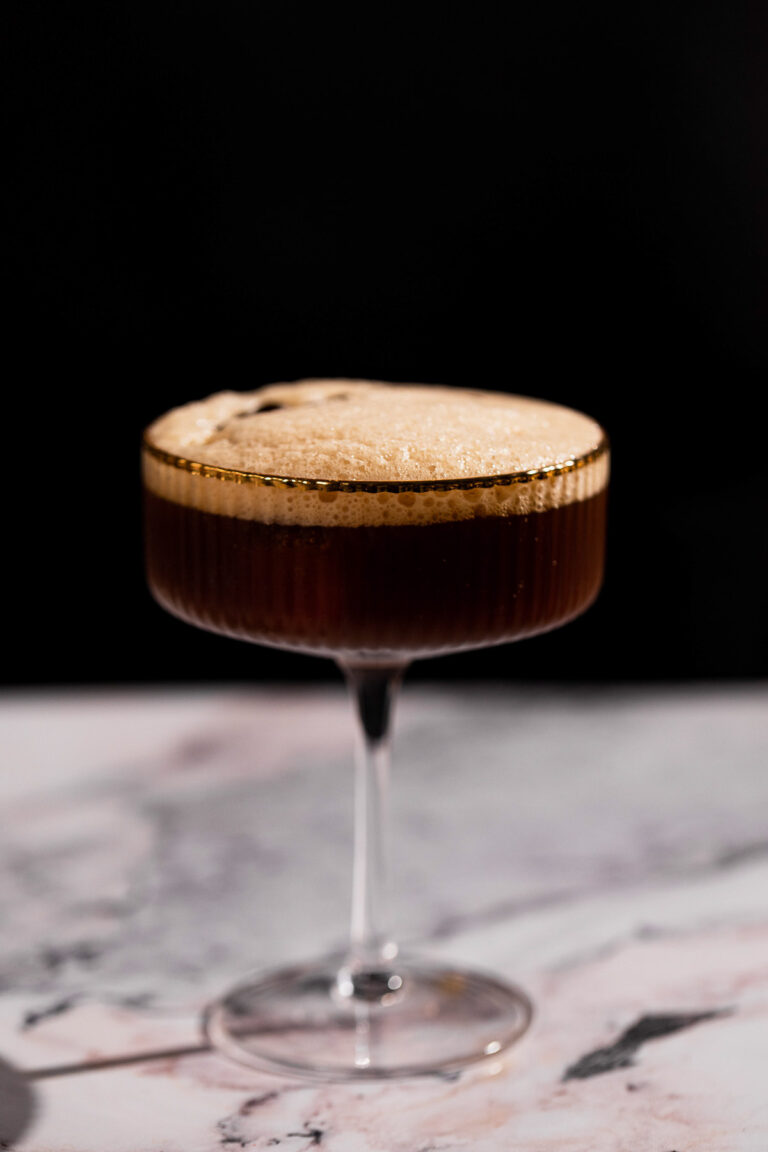 Beautiful frothy carajillo cocktail in a coupe glass.