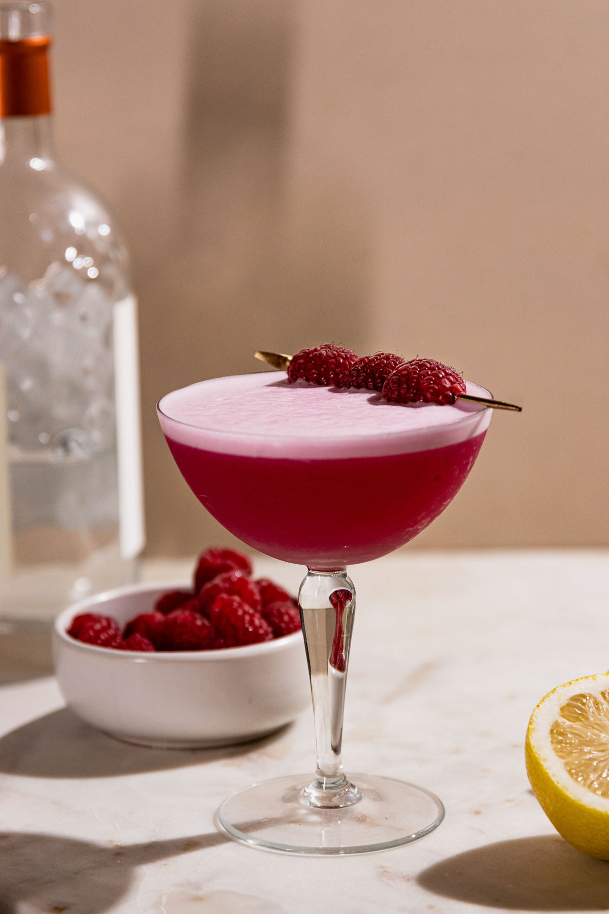 Fun pink drink, the clover club in a coupe glass, garnished with raspberries.