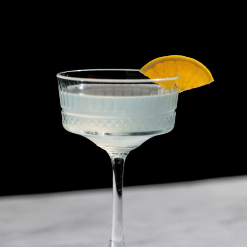 Corpse Reviver cocktail with an orange wedge in a cocktail glass.