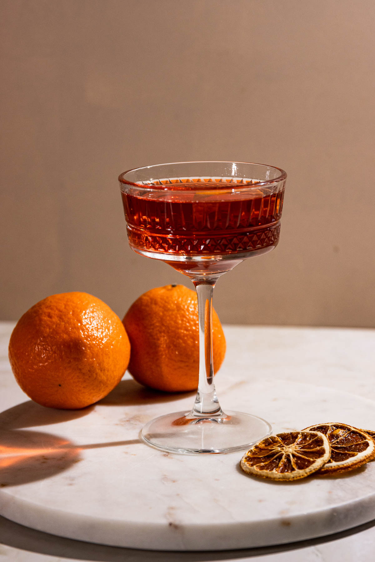 An el presidente cocktail on a white table with oranges.