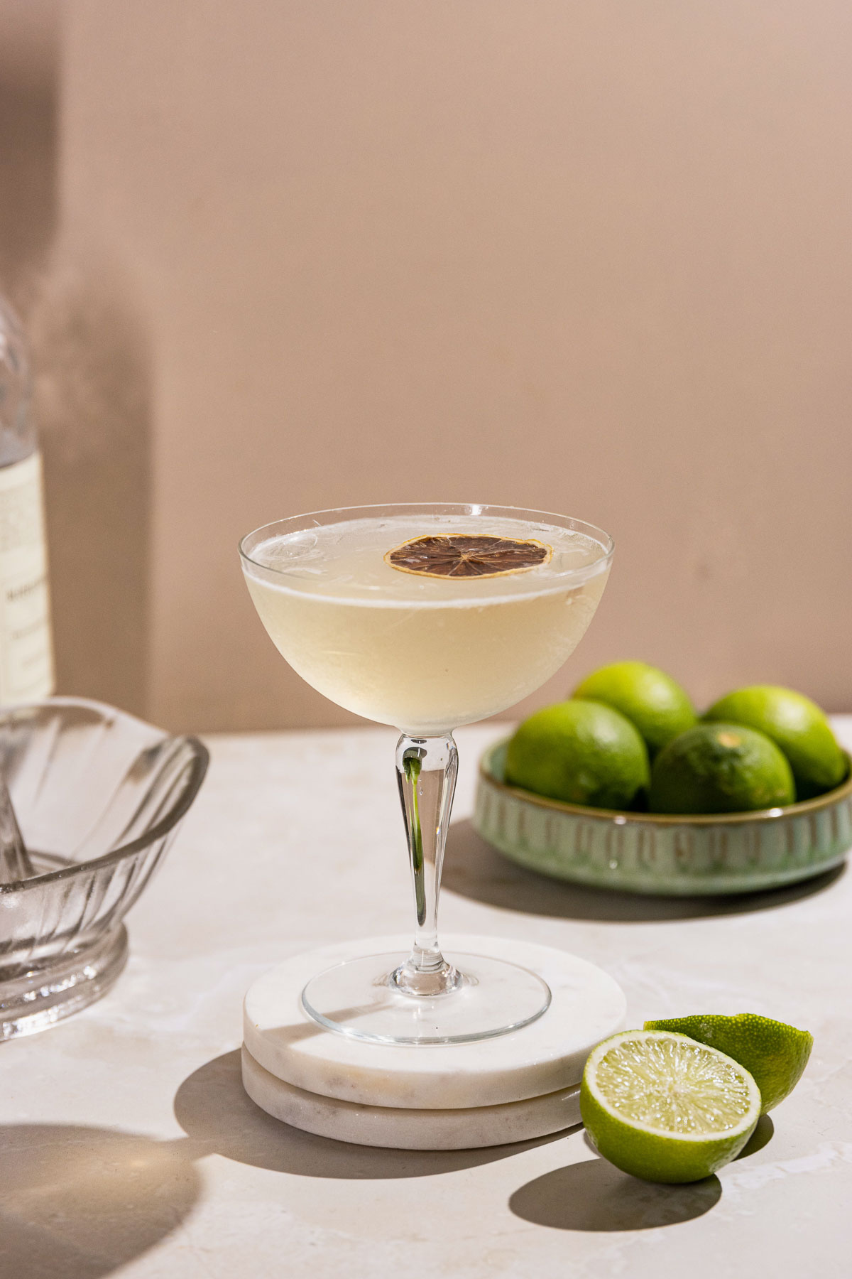 Gimlet cocktail in a coupe glass with a dehydrated lime slice.