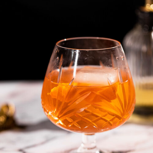 Mezcal old fashioned in a snifter glass with craft ice.