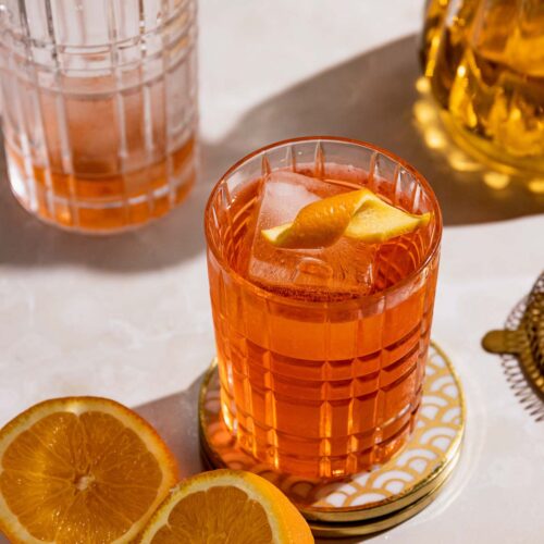 Negroni drink in a highball glass with orange twist.