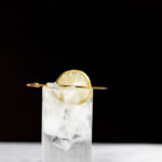 Tom Collins cocktail in a highball glass with a lemon slice.