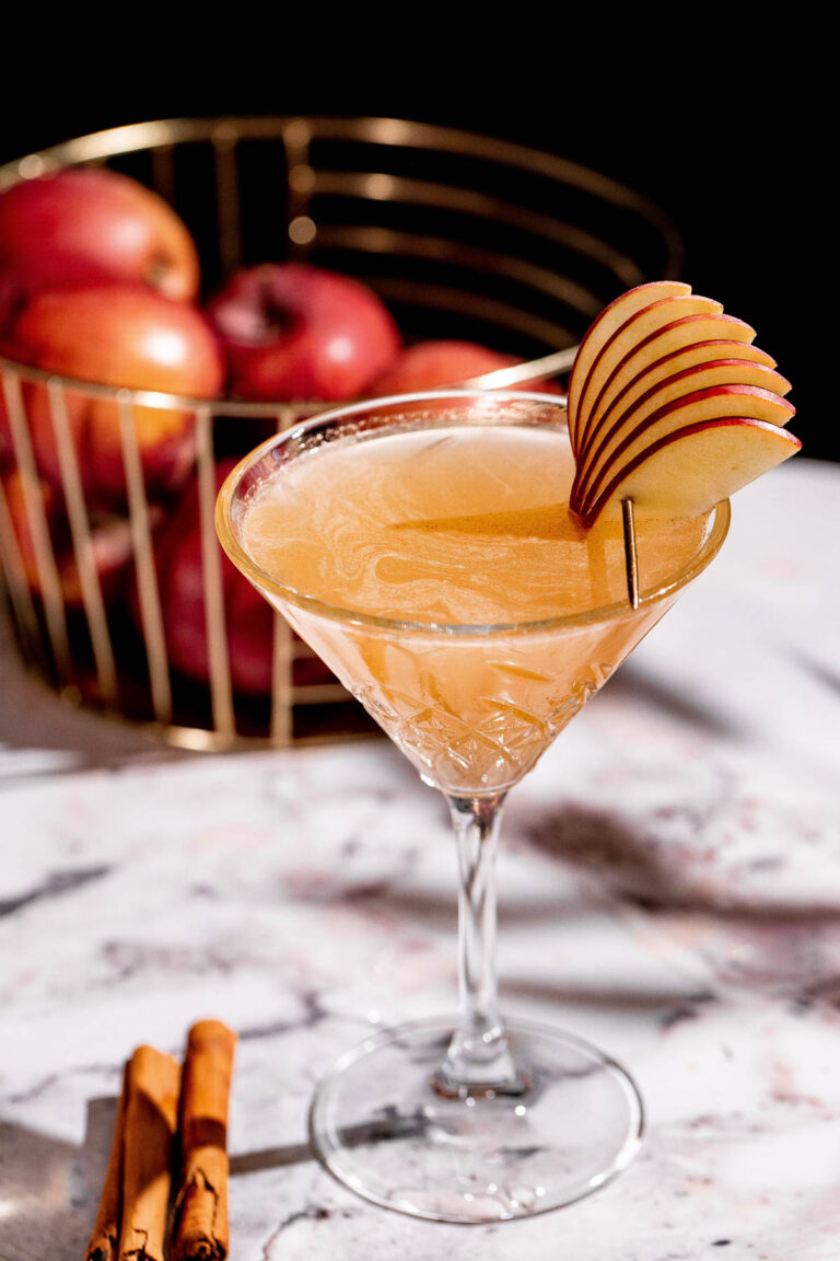 Apple cider martini in a cocktail glass garnished with apple slices.