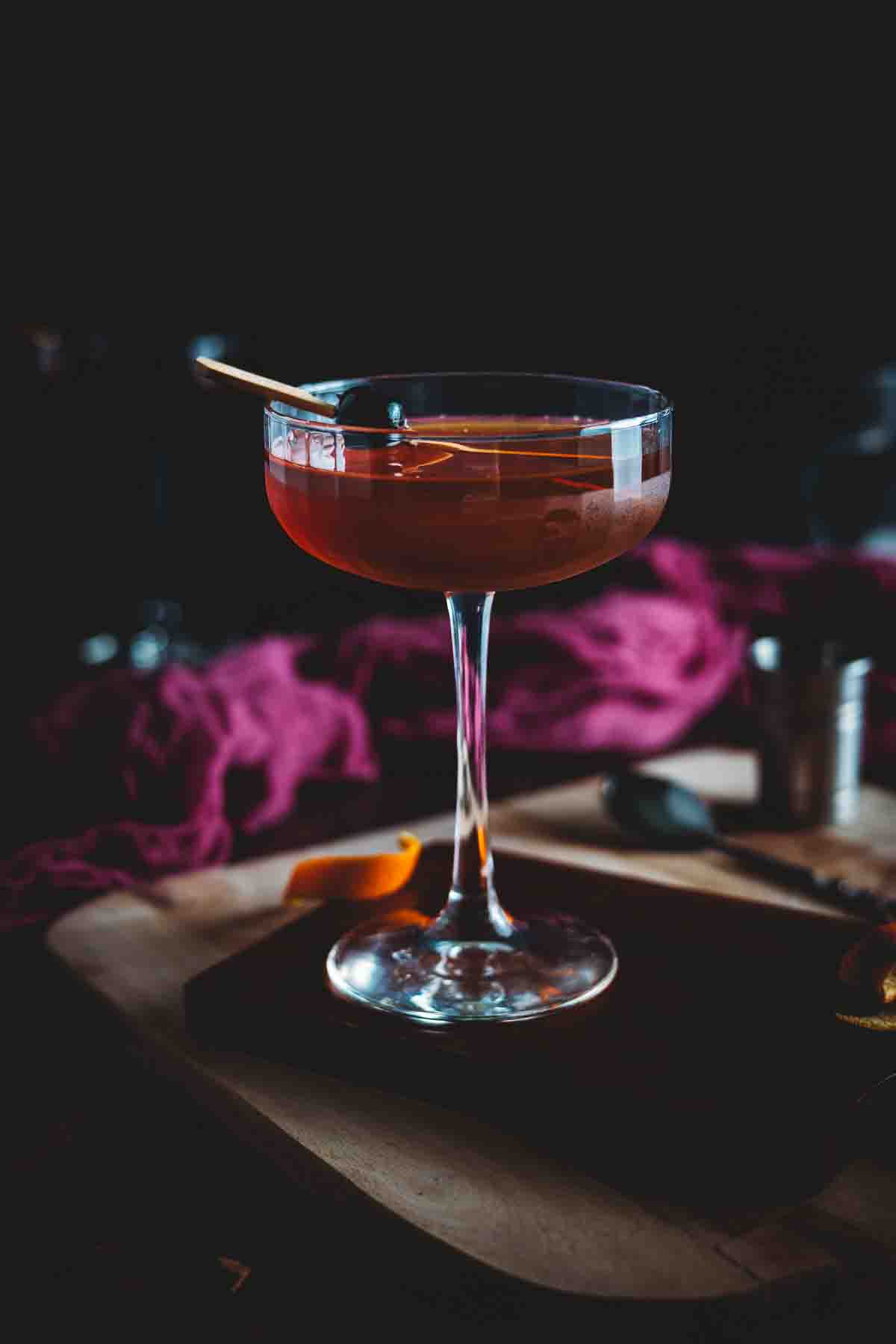 Smoked manhattan cocktail with a cherry garnish.
