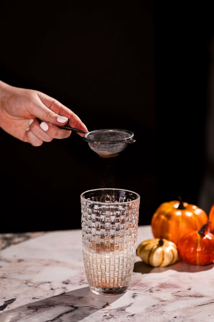 Pumpkin pie spice being sprinkled through a mesh basket.