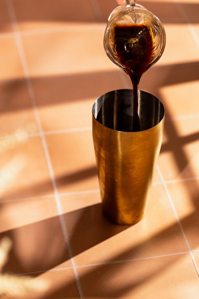 Espresso being poured into a cocktail shaker.