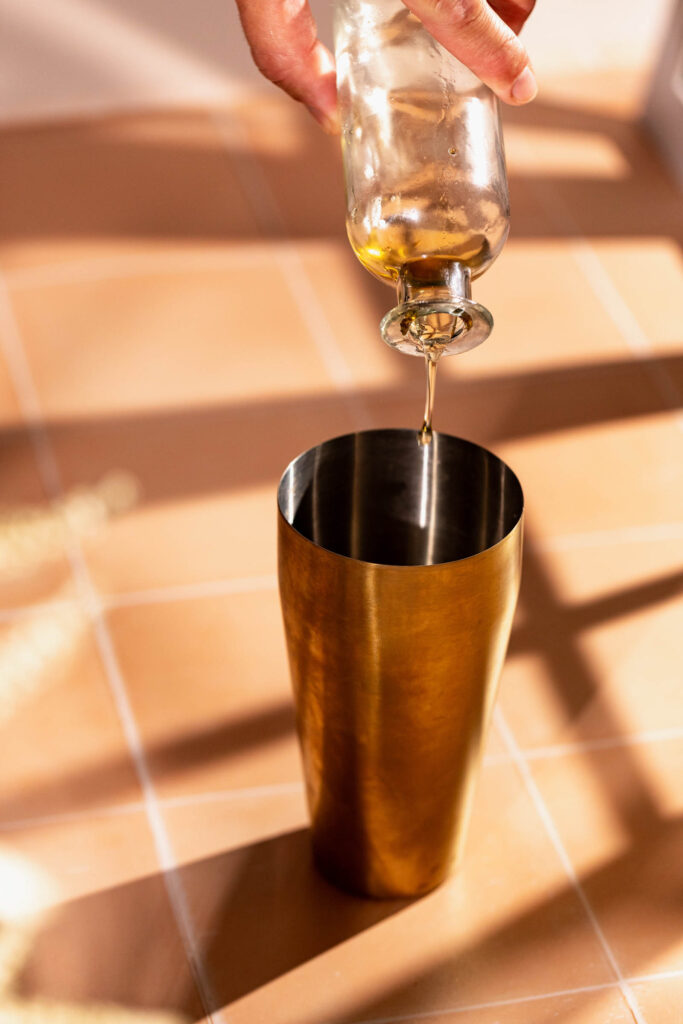 Brown sugar syrup being poured into a cocktail shaker.