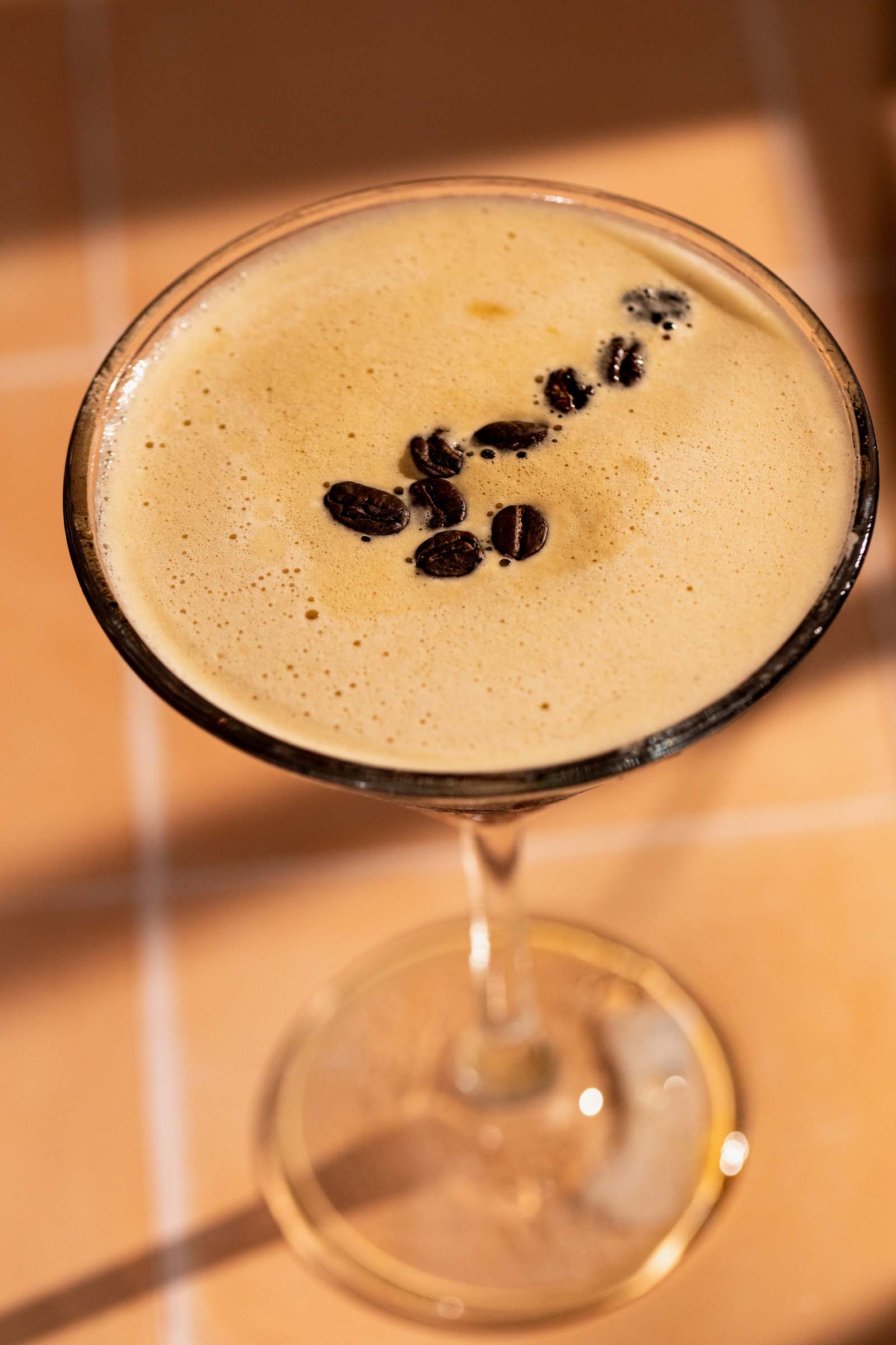 Coffee beans floating atop a frothy espresso martini.