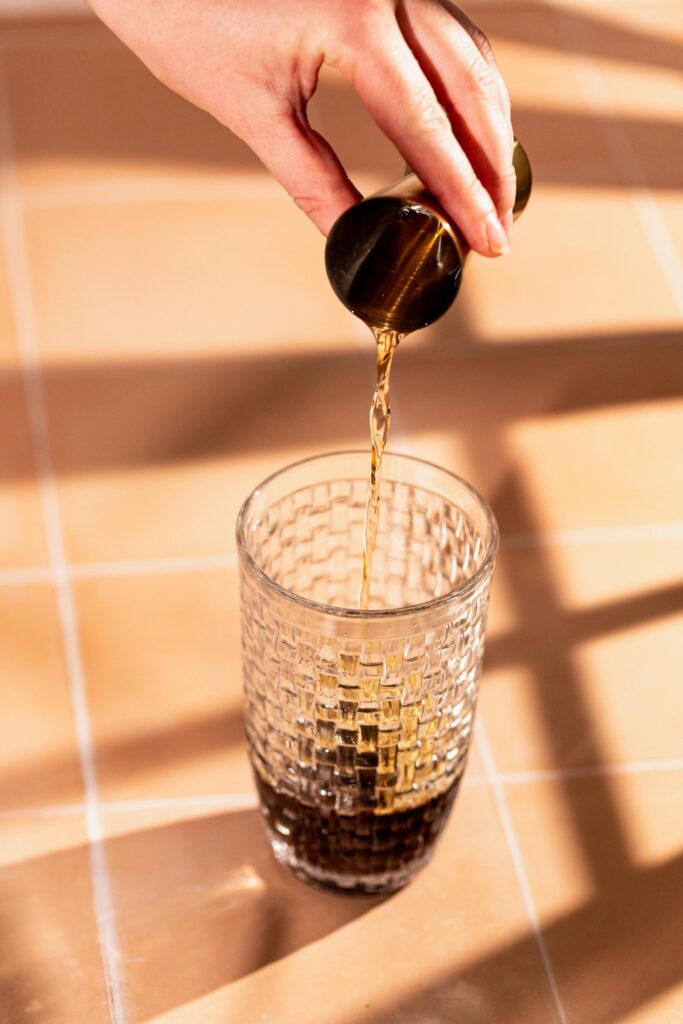 Borubon is poured from a small cup into a textured glass on a tiled surface.