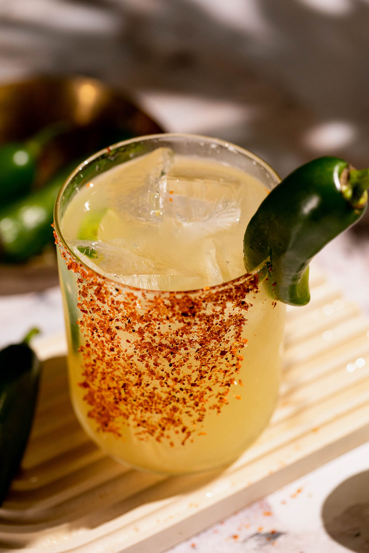 A glass of spicy margarita beverage features a chili powder rim and jalapeño garnish.