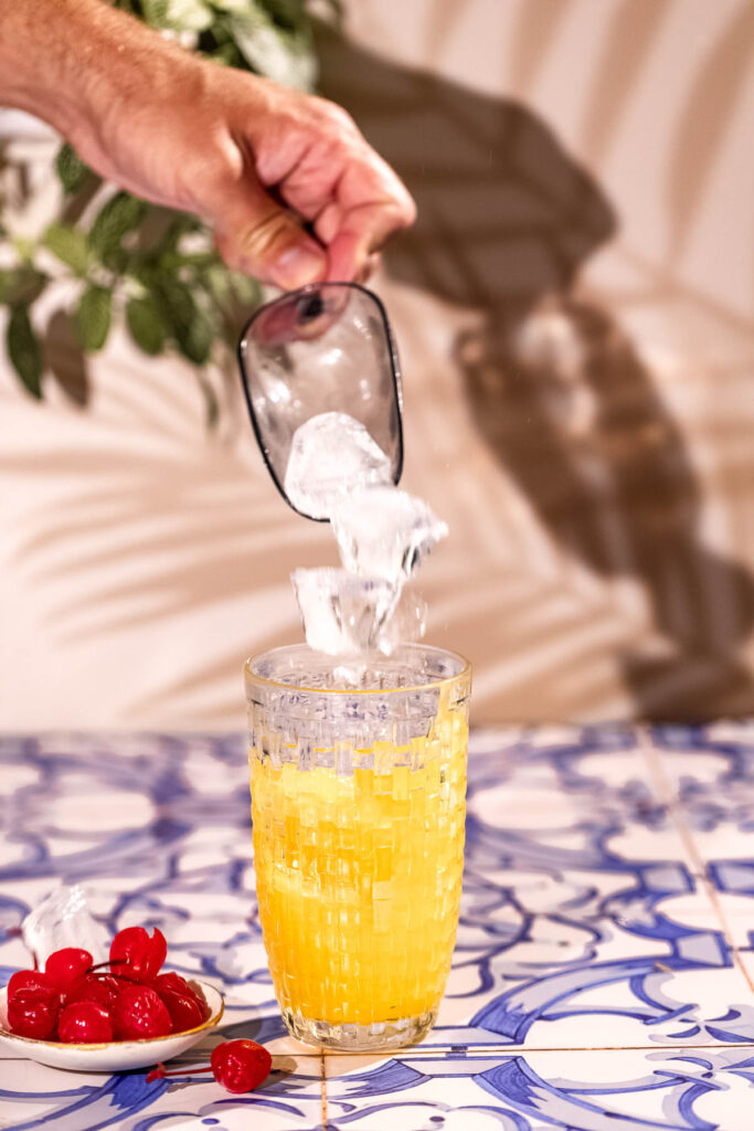 Ice splashing into the cocktail shaker filled with juice and rum.