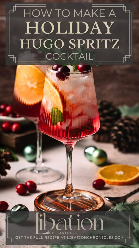 A festive cocktail in a stemmed glass with cranberries, mint, and orange slice, amid pinecones, greenery, and holiday decor.